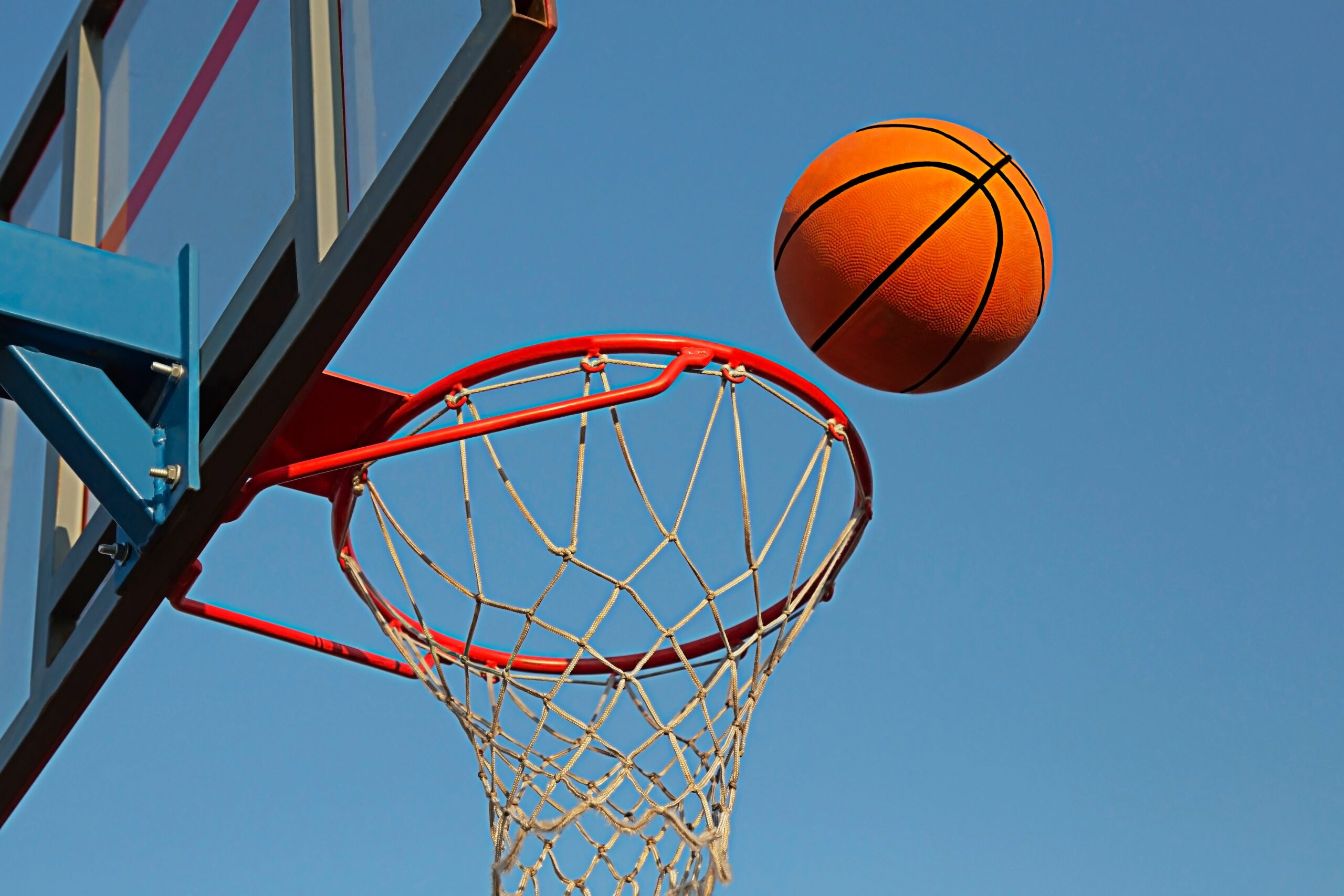 A,Basketball,In,A,Net,On,A,Blue,Sky,Background.